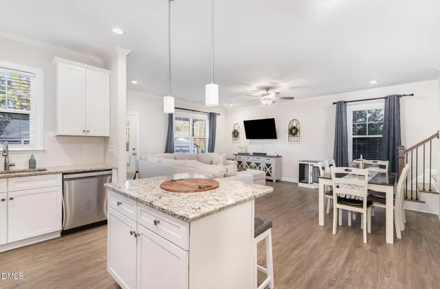 a kitchen with a dining table chairs sink and white cabinets