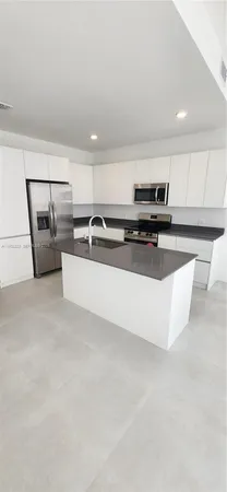 a living room with stainless steel appliances furniture and a kitchen view