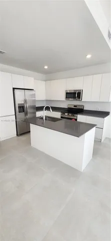 a living room with stainless steel appliances furniture and a kitchen view