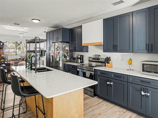 a kitchen with stainless steel appliances kitchen island a table chairs in it and wooden floors