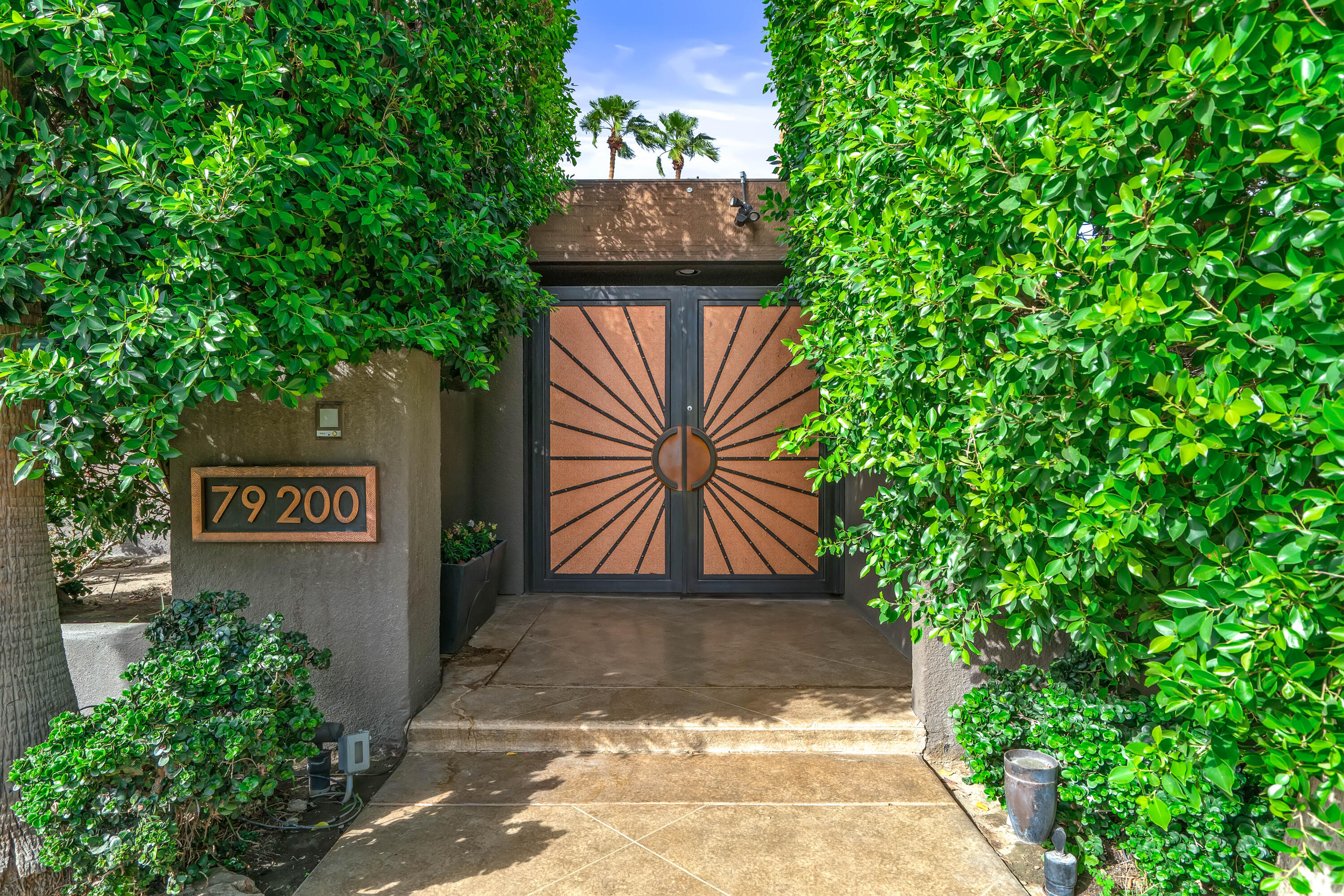 79200 Jack Rabbit Trail La Quinta, CA 92253 - Photo 7 of 76 a view of a street with potted plants and a large tree
