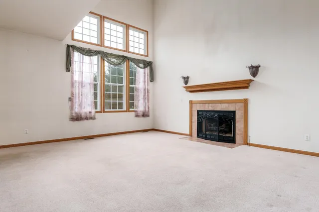 an empty room with windows and fireplace