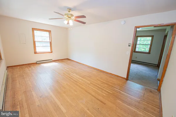a view of an empty room with a window and wooden floor