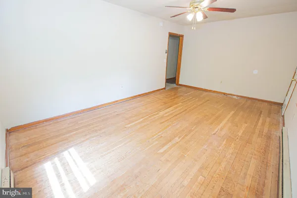 en empty room with wooden floor and fan