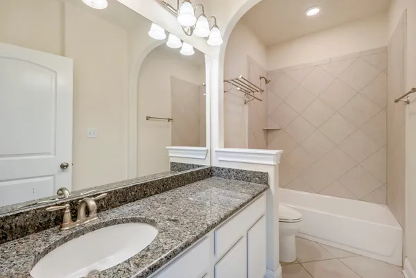 a bathroom with a granite countertop bathtub a sink and a mirror
