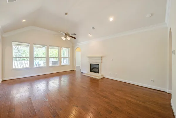 an empty room with wooden floor fireplace and windows