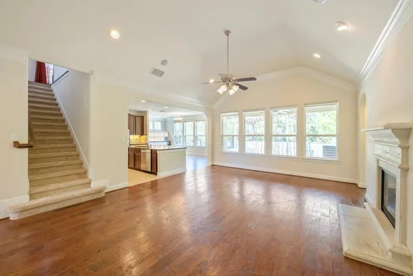 an empty room with wooden floor fireplace and windows