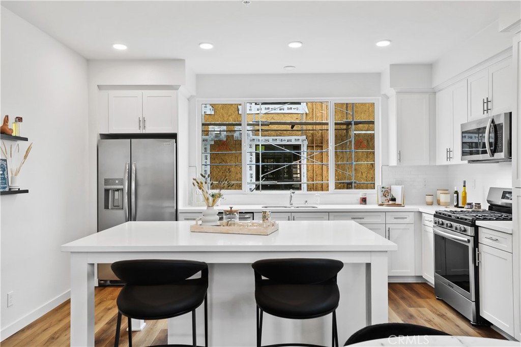53 Bigsby Drive Stanton, CA 90680 - Photo 26 of 48 a kitchen with stainless steel appliances granite countertop a stove a sink a microwave a dining table and chairs