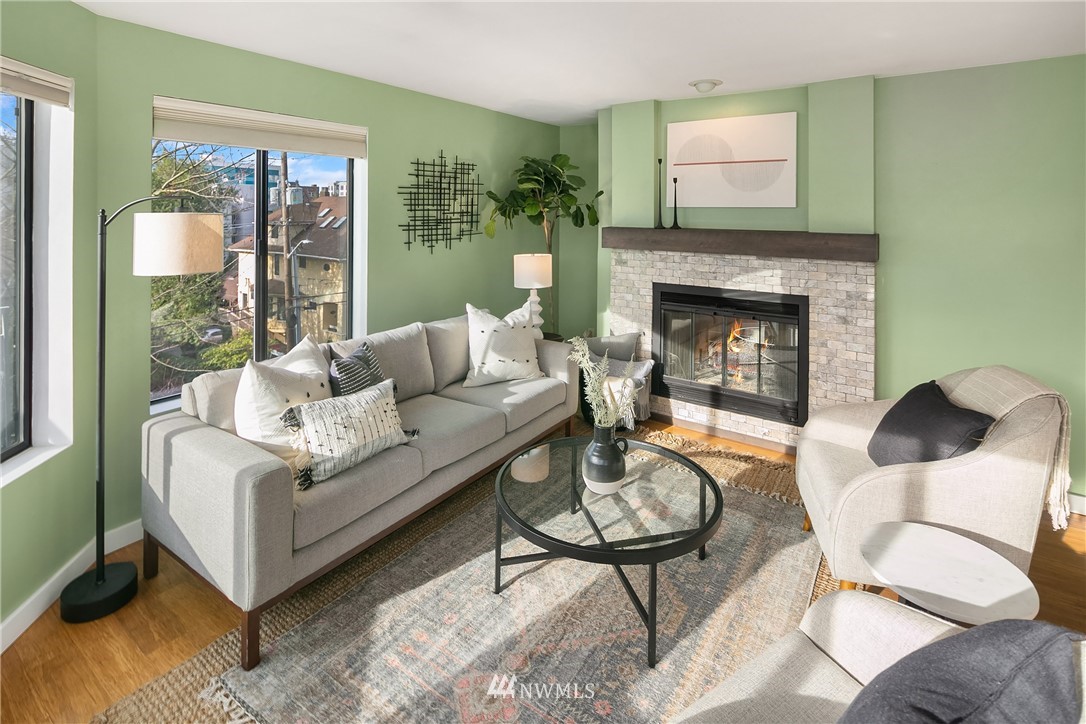 116 11th Avenue East, Unit 402 Seattle, WA 98102 - Photo 4 of 22 a living room with furniture a table and a fireplace