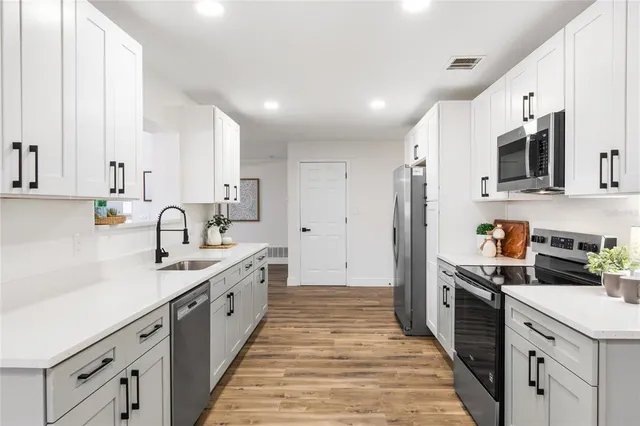 a kitchen with white cabinets sink and stainless steel appliances