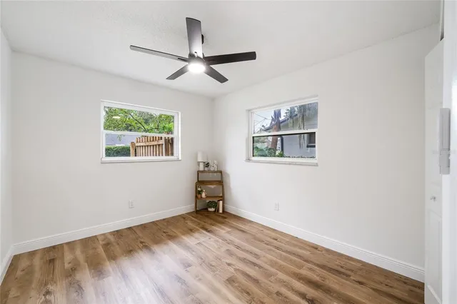 a view of empty room with wooden floor and fan