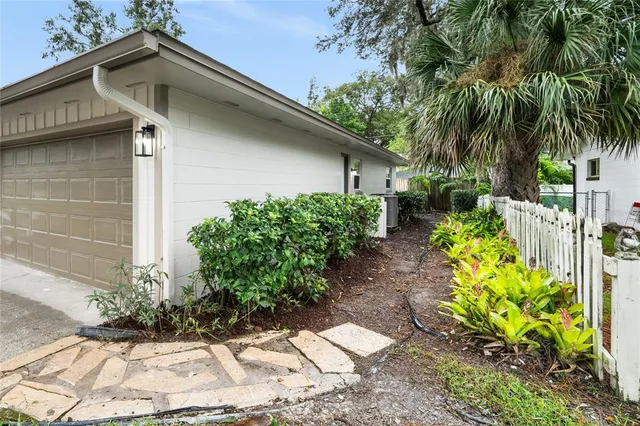 a white house that has a small yard and a big trees with wooden fence