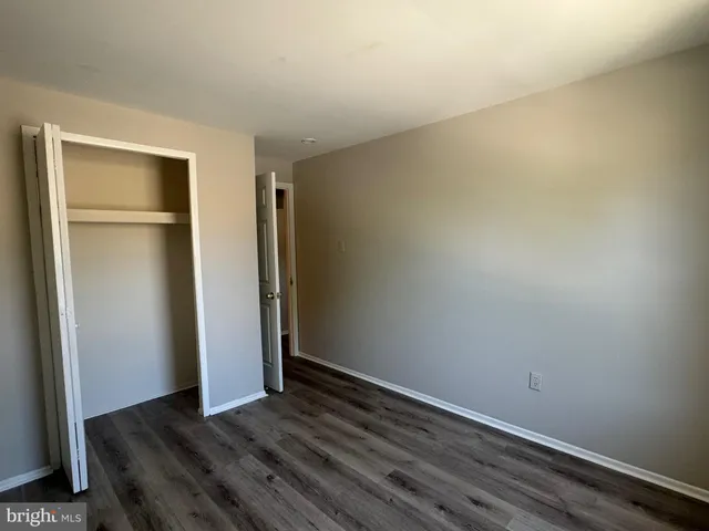 a view of an empty room with closet and wooden floor