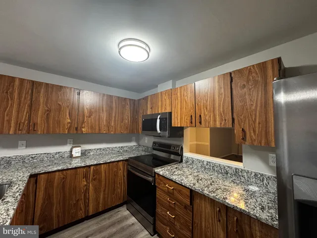 a kitchen with granite countertop stainless steel appliances a sink stove and refrigerator