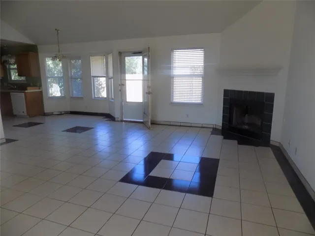 an empty room with windows and fireplace