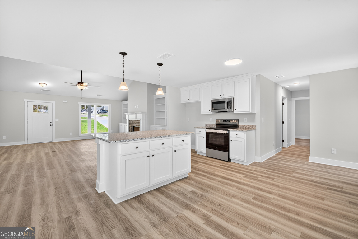 271 Mockingbird Lane, Unit 20 Winder, GA 30680 - Photo 14 of 38 a large kitchen with stainless steel appliances granite countertop a stove and a wooden floors