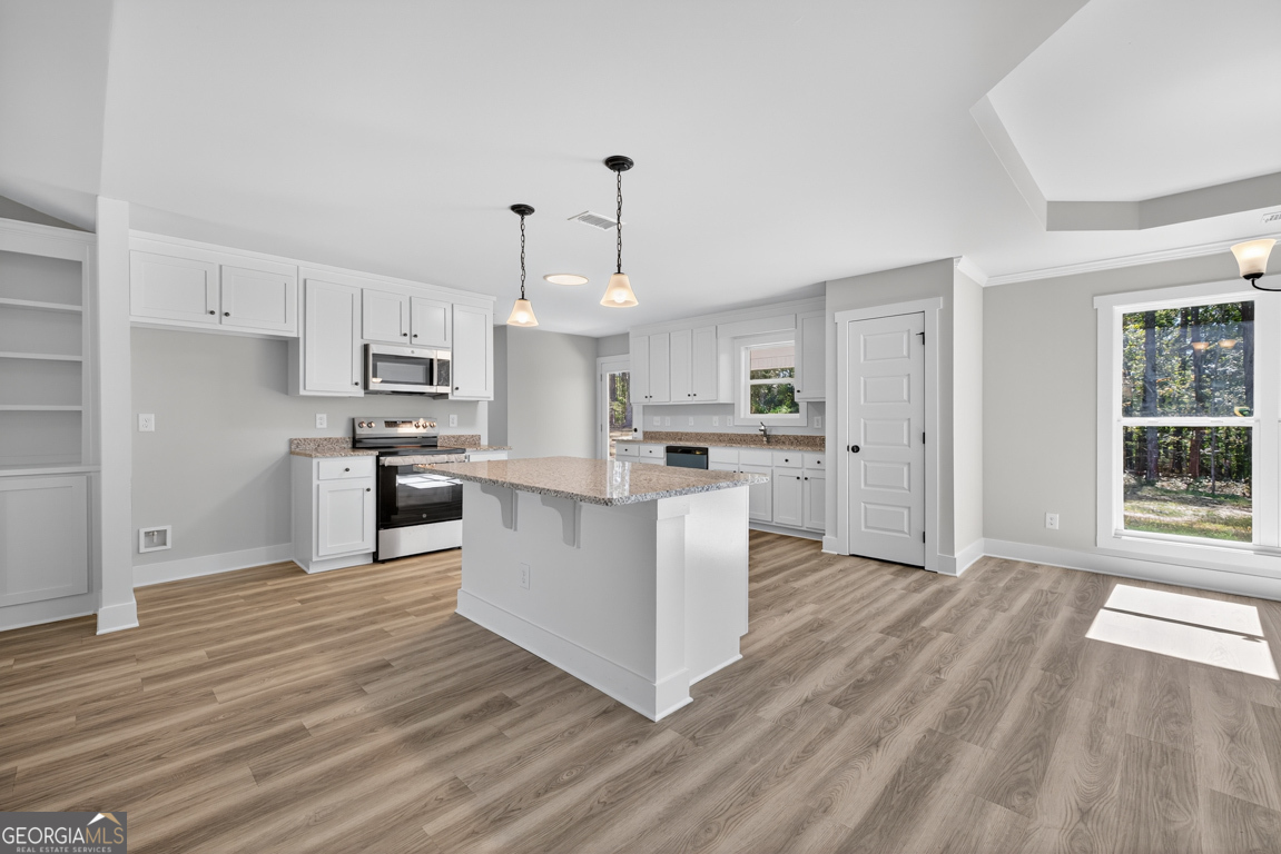 271 Mockingbird Lane, Unit 20 Winder, GA 30680 - Photo 10 of 38 a kitchen with stainless steel appliances kitchen island wooden floors and white cabinets