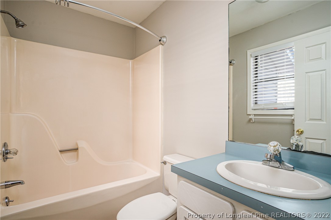215 Fox Run Road Pinehurst, NC 28374 - Photo 14 of 24 a bathroom with a granite countertop sink toilet a mirror and a tub