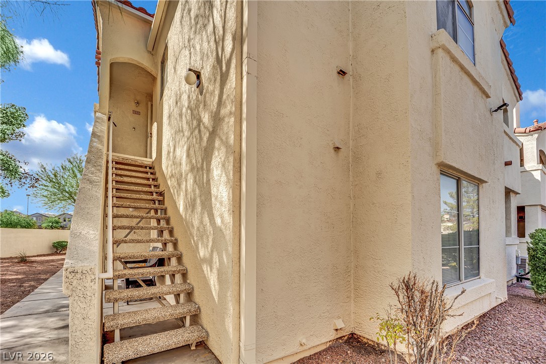 698 South Racetrack Road, Unit 1521 Henderson, NV 89015 - Photo 29 of 33 A private exterior staircase leads to an upper-level entry, framed by stucco siding and low-maintenance landscaping.