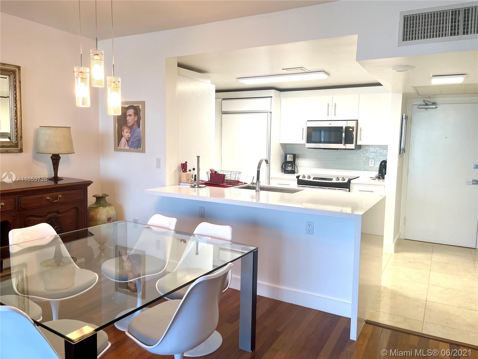 10275 Collins Avenue, Unit 425 Bal Harbour, FL 33154 - Photo 2 of 18 a kitchen with stainless steel appliances a sink and a table with chairs