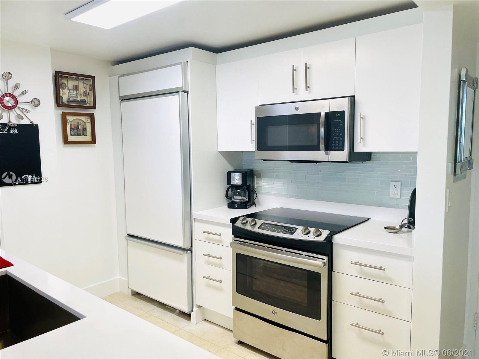 10275 Collins Avenue, Unit 425 Bal Harbour, FL 33154 - Photo 3 of 18 a kitchen with cabinets stainless steel appliances and wooden floor