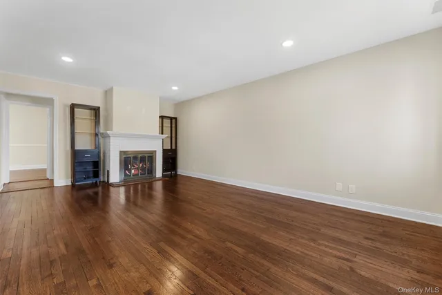 a view of empty room with wooden floor and fireplace