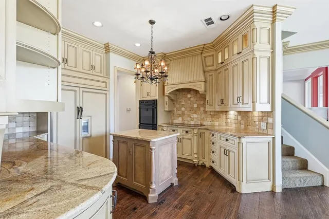 a large white kitchen with stainless steel appliances granite countertop a lot of counter space and wooden floors