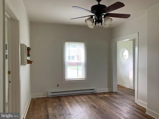 a view of empty room with wooden floor and fan