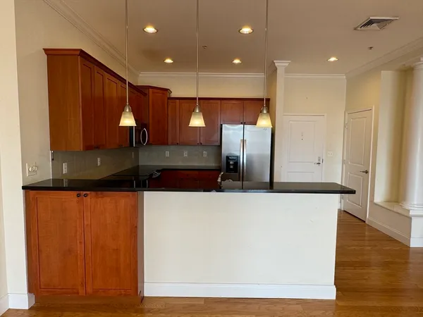 a large kitchen with stainless steel appliances wooden cabinets and a wooden floor