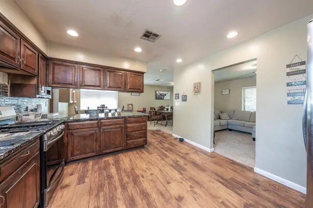 a kitchen with stainless steel appliances granite countertop wooden cabinets a stove top oven a sink and dishwasher