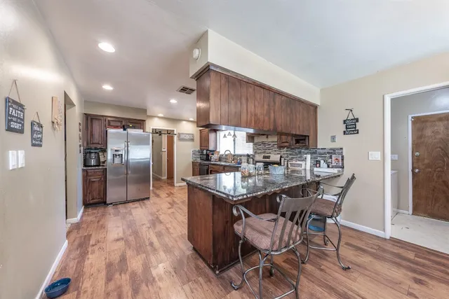 a kitchen with stainless steel appliances granite countertop a kitchen island hardwood floor and a sink