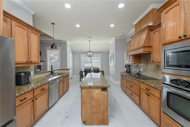 a large kitchen with stainless steel appliances granite countertop a stove top oven a sink dishwasher a dining table and chairs with wooden floor