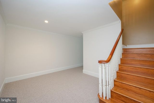a view of a lake with lawn chairs and large trees