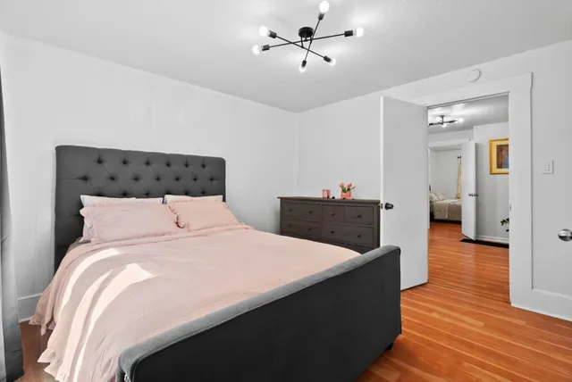 a large bedroom with wooden floor and ceiling fan