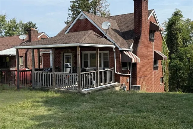 a view of a house with a yard and a large tree