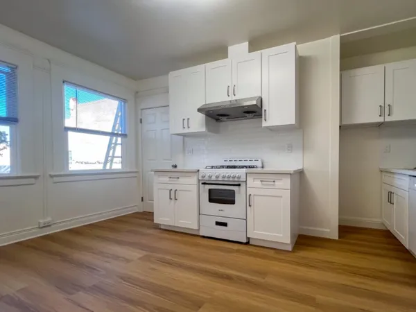 a kitchen with stainless steel appliances white cabinets and a wooden floor