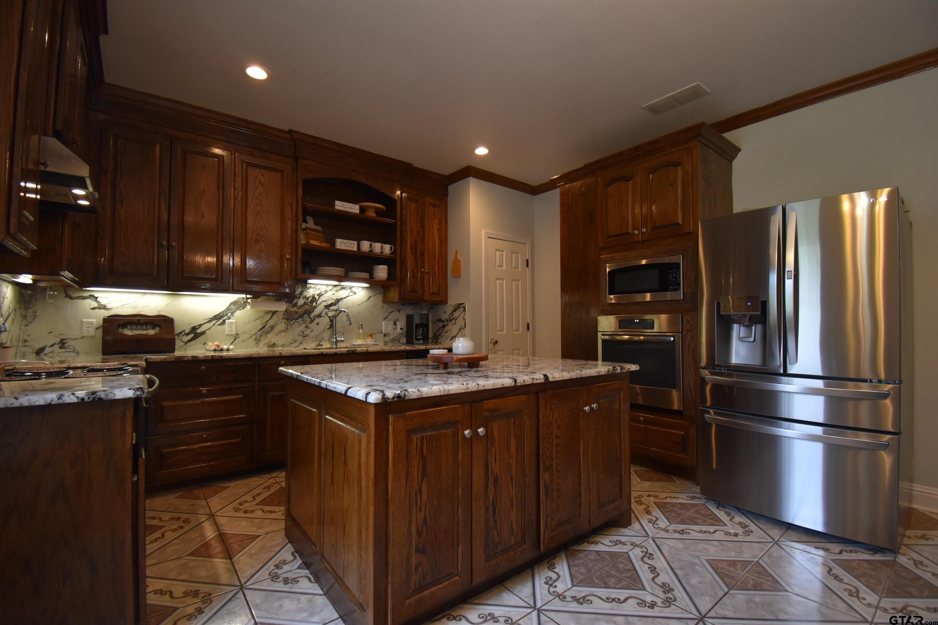 7727 Knowles Trace Tyler, TX 75708 - Photo 14 of 34 a kitchen with stainless steel appliances granite countertop a stove a refrigerator and a sink