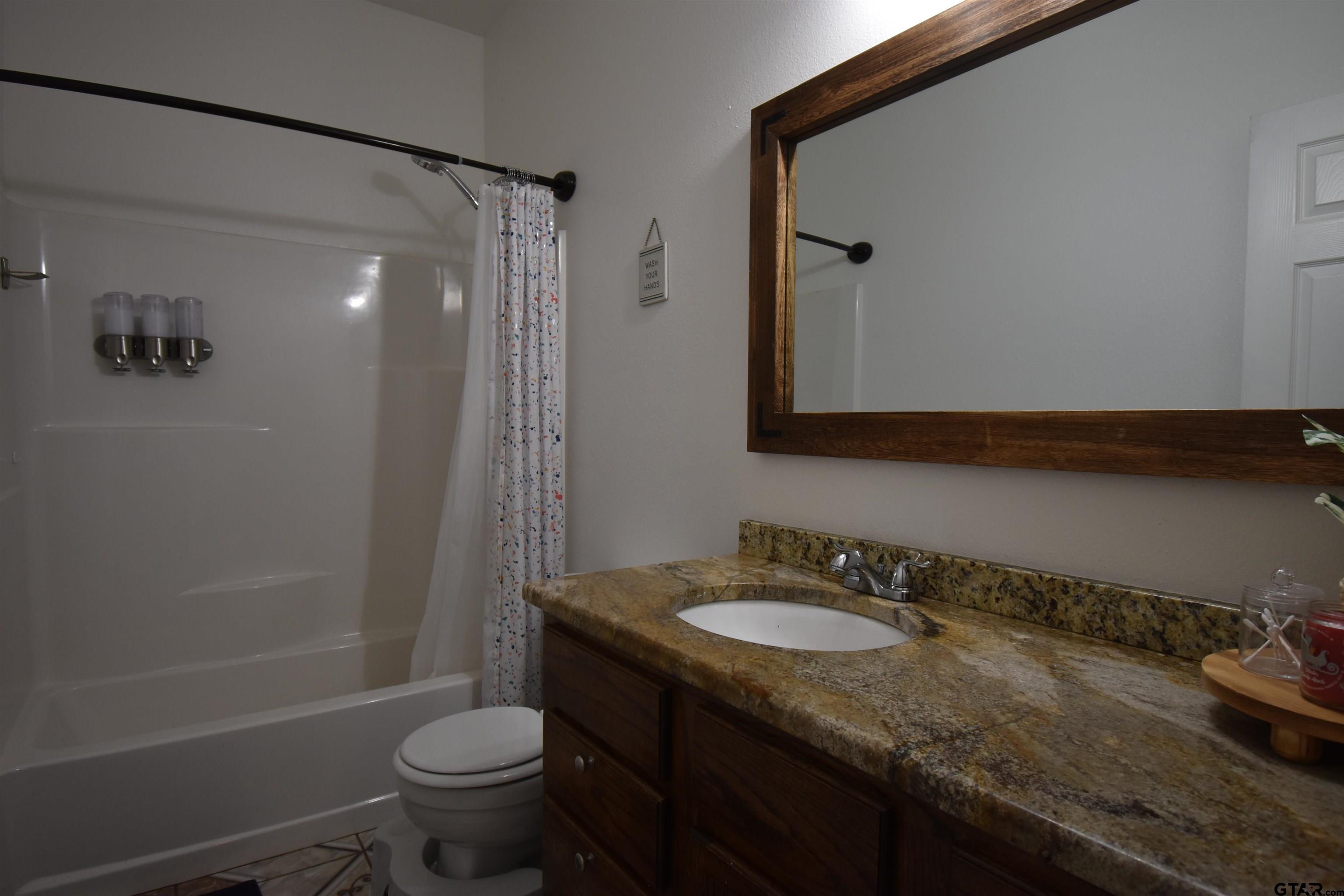 7727 Knowles Trace Tyler, TX 75708 - Photo 25 of 34 a bathroom with a granite countertop sink toilet and shower