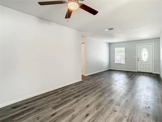 a view of an empty room with window and wooden floor