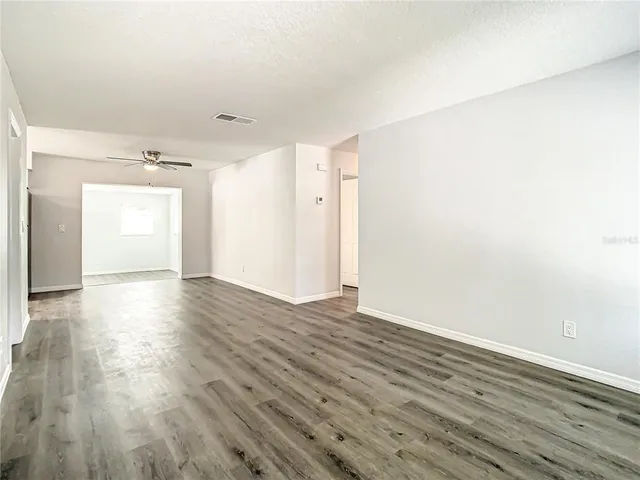a view of empty room with wooden floor and fan