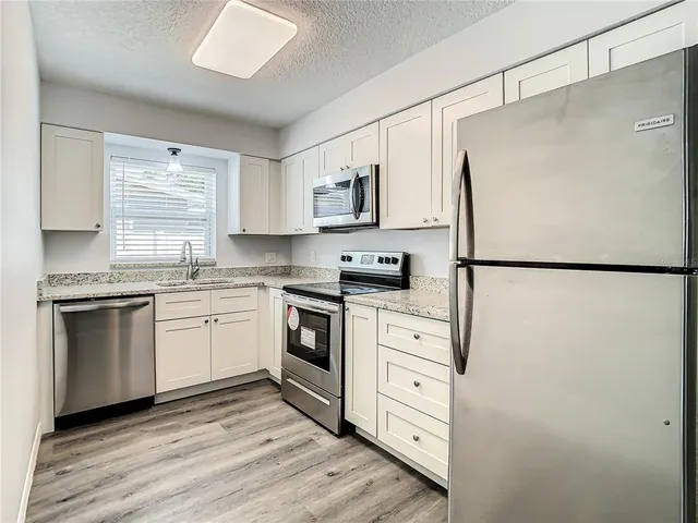 a kitchen with white cabinets stainless steel appliances and sink