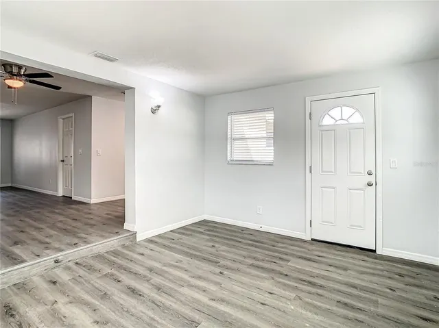 an empty room with wooden floor cabinet and windows
