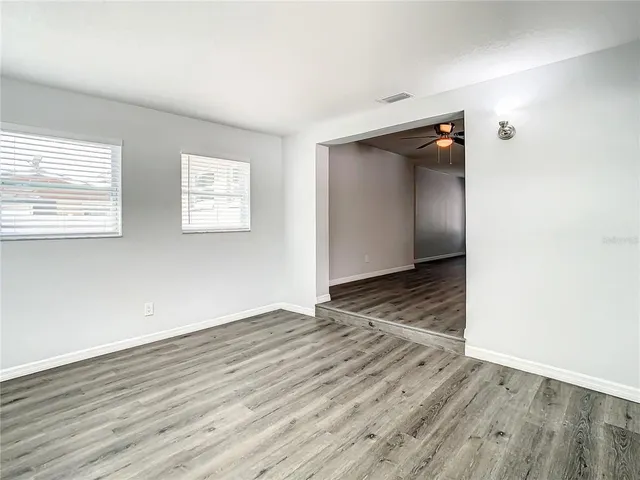 a view of an empty room with wooden floor and a window