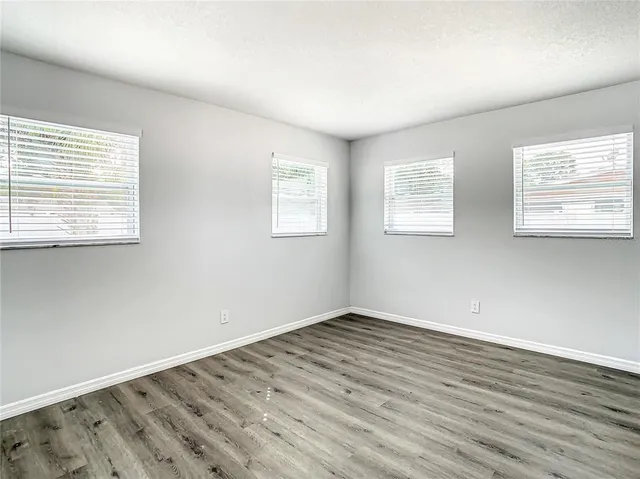 a view of an empty room with wooden floor and a window
