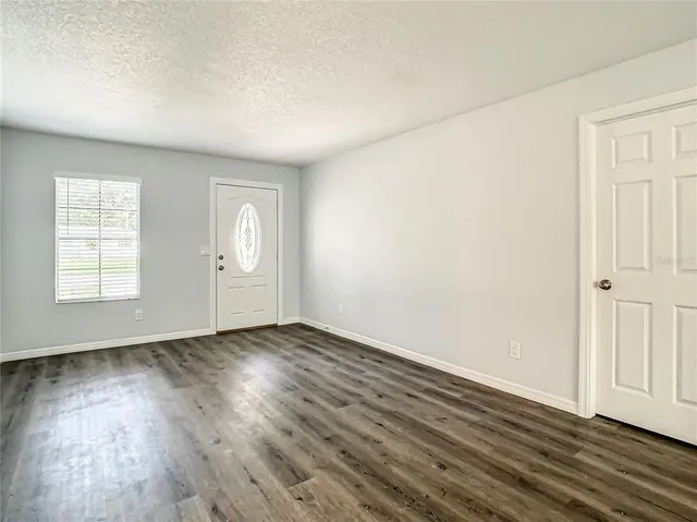 an empty room with wooden floor and windows