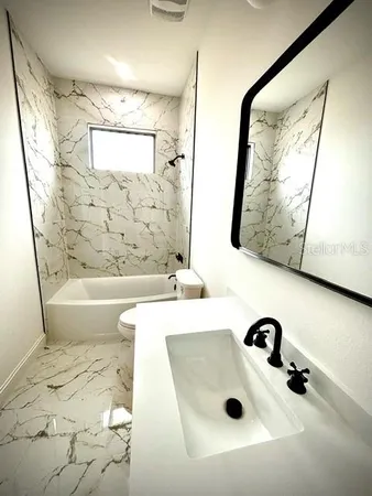 a bathroom with a tub a sink and a mirror