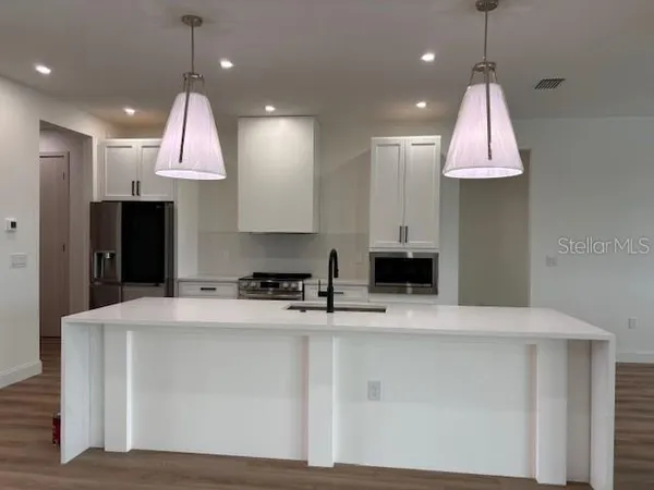 a kitchen with kitchen island granite countertop a sink a stove and a refrigerator