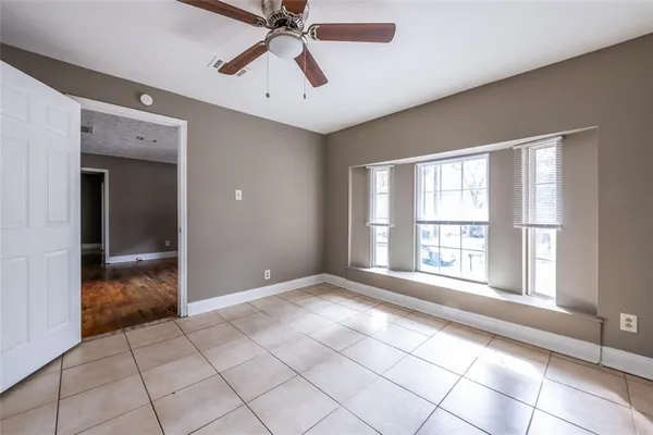 a view of an empty room with window and chandelier fan