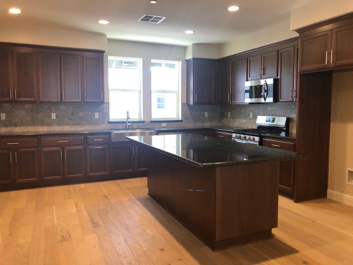 a kitchen with stainless steel appliances granite countertop a sink a stove a refrigerator cabinets and a window