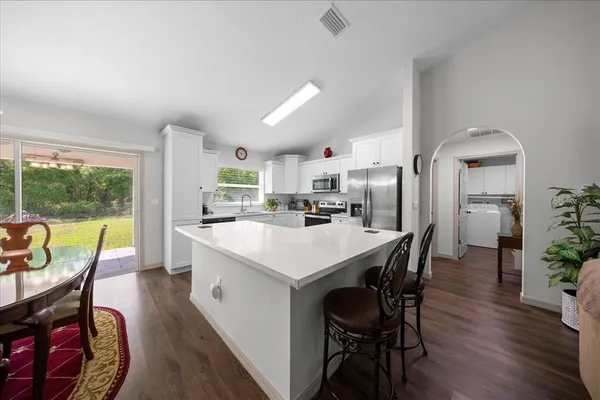 a kitchen with stainless steel appliances a dining table chairs a sink and a refrigerator